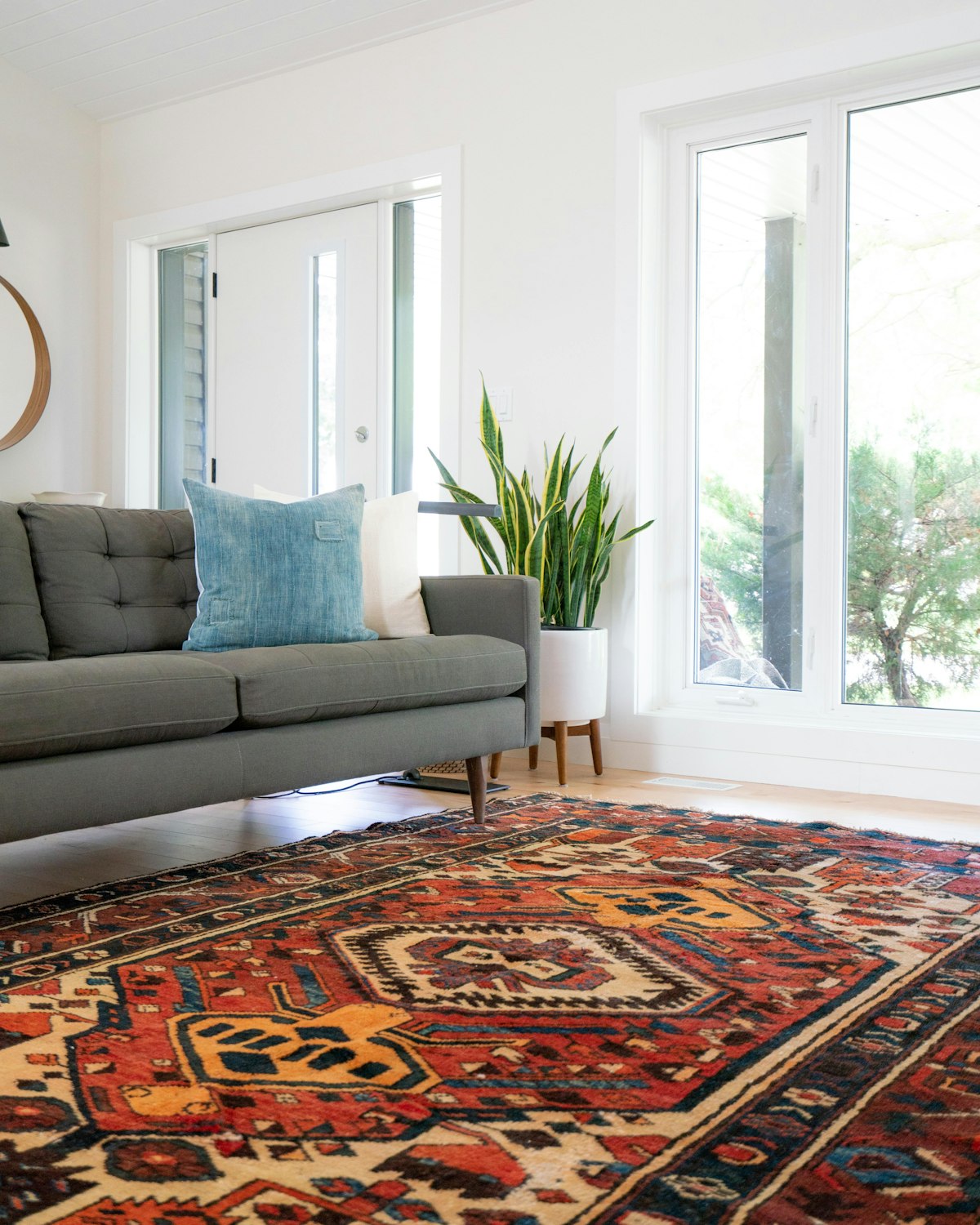 Grey sofa on a red patterned area rug in a bright room