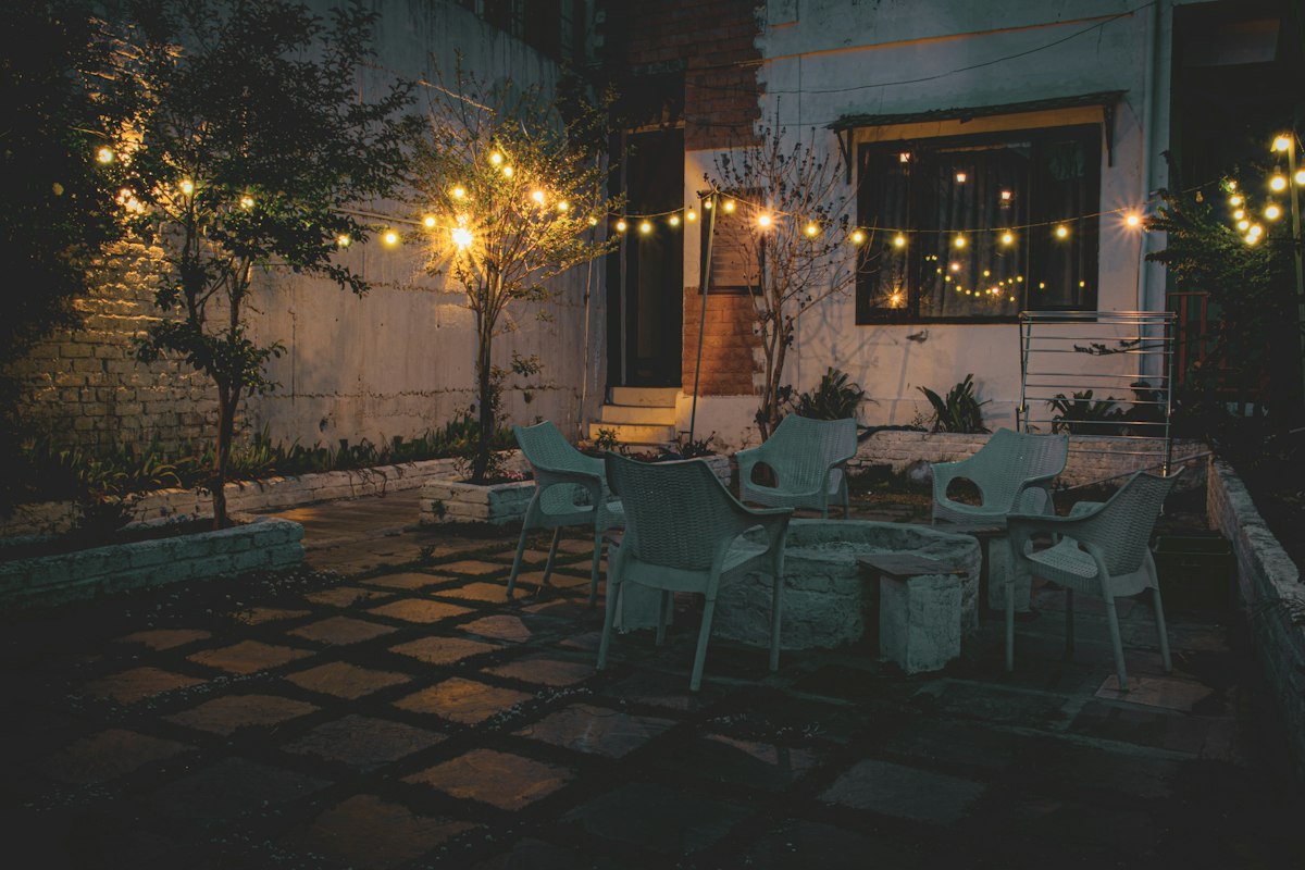 Patio chairs under warm string lights at night